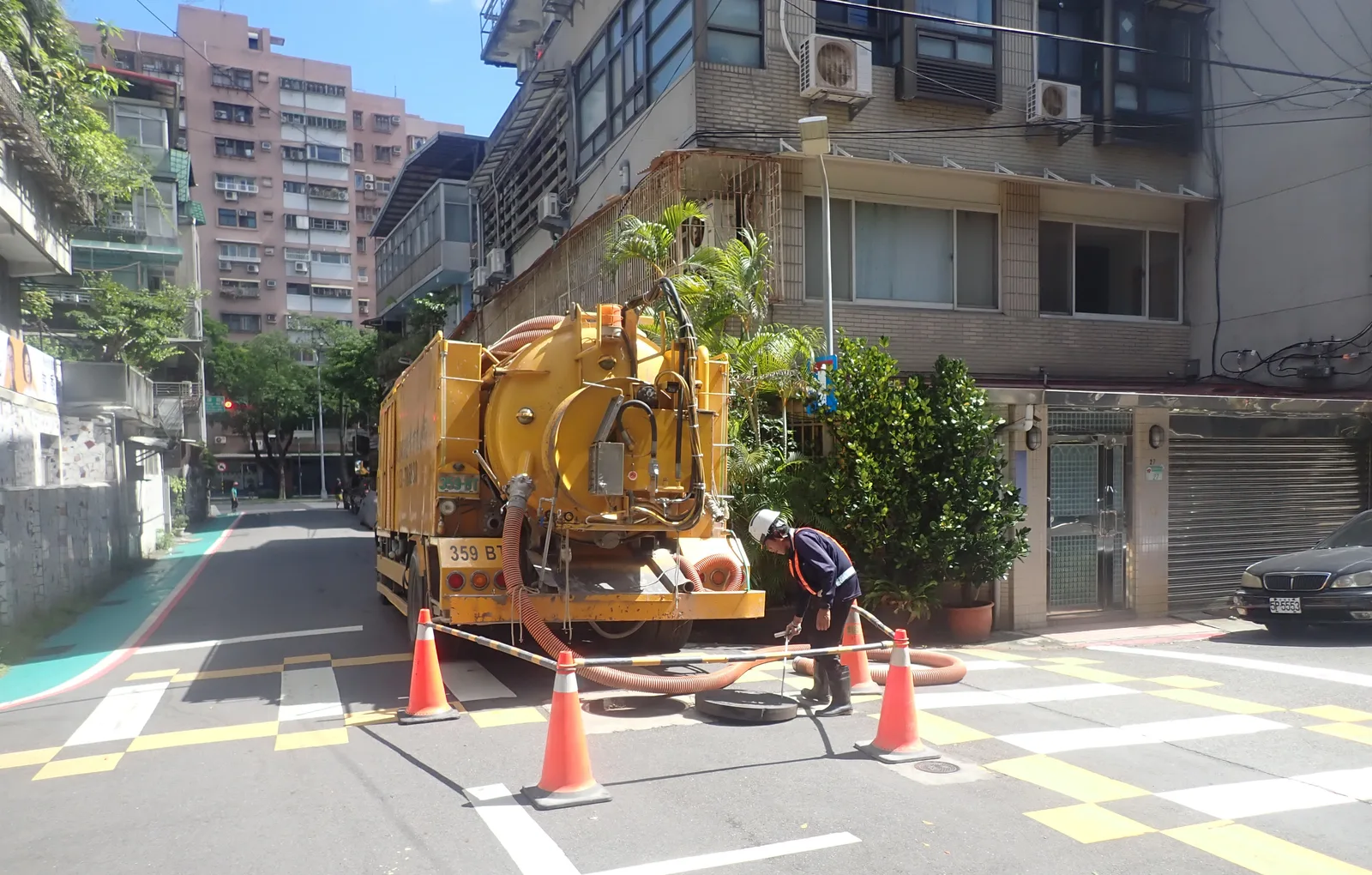 黃色清溝車停在路口，三角錐圍出作業範圍