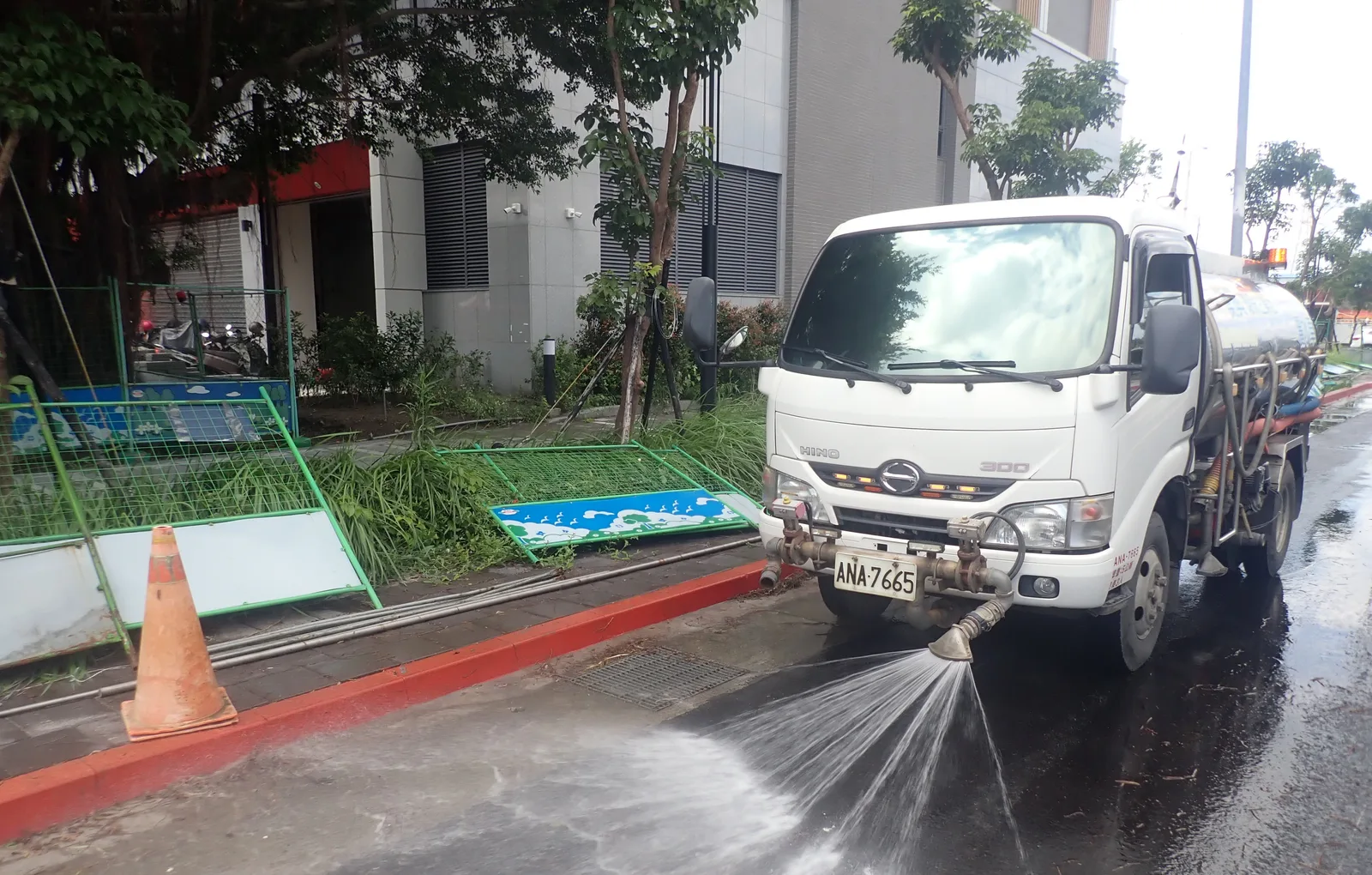 白色水車沿著路邊噴水，清洗路面