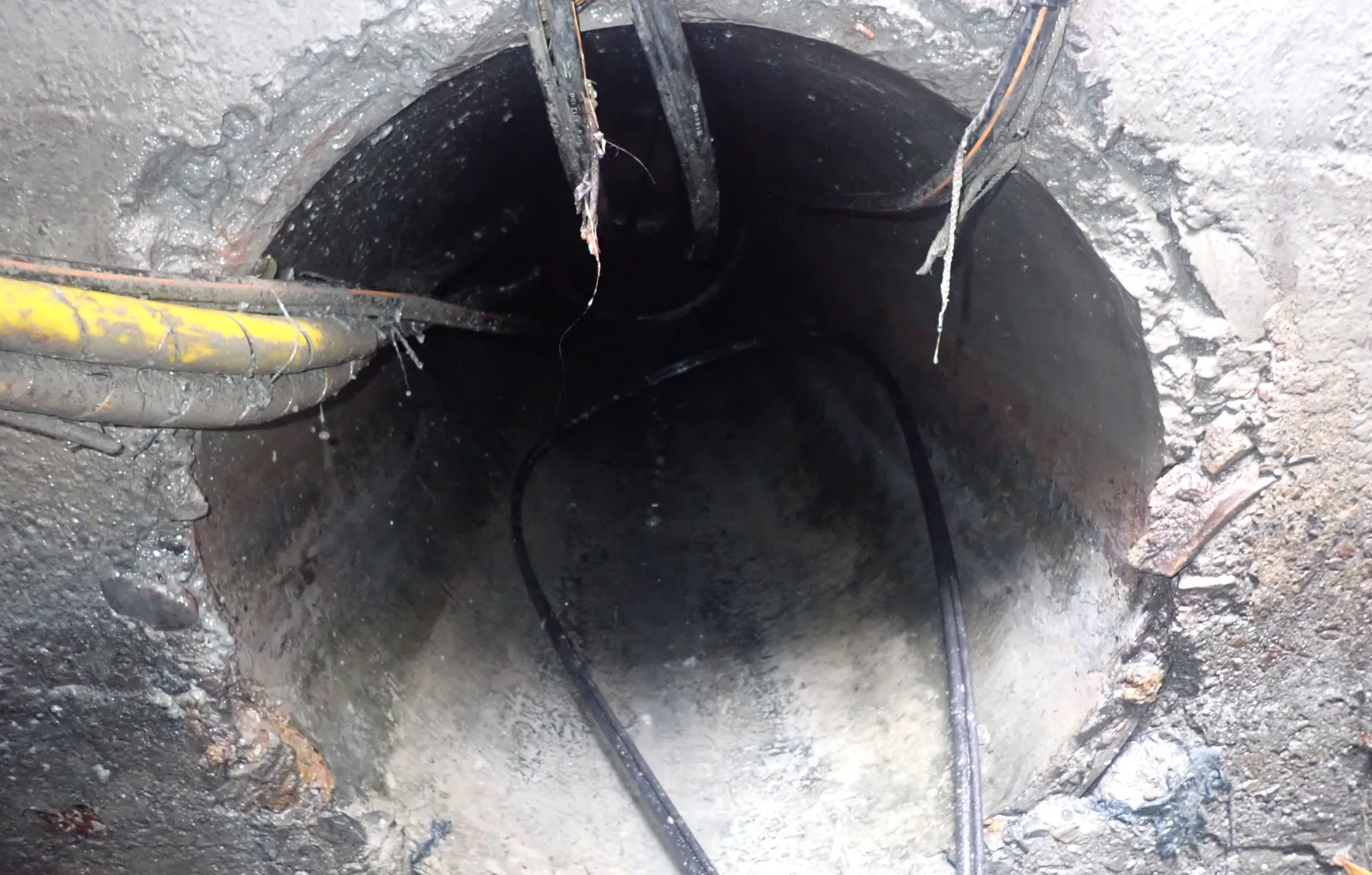 圓形涵管管口內部，電纜從上方穿過，管底露出管壁