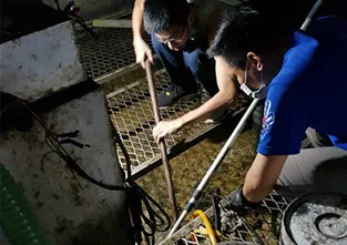 兩位師傅在格柵旁拿長桿作業